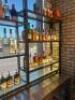 DESCRIPTION 9' THREE-SECTION CUSTOM METAL RACK WITH GLASS INSERT SHELVING, DESIGNED FOR BACK BAR BOTTLE DISPLAY. BUILT TO FIT AN 84" BACK BAR COOLER O - 4