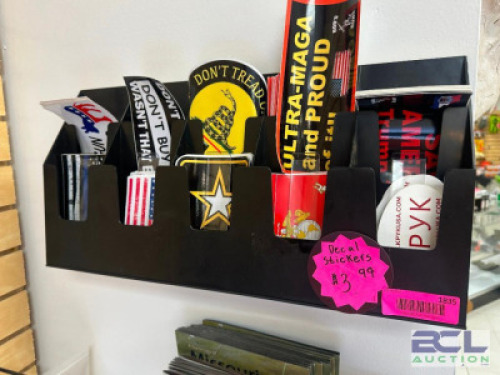 DESCRIPTION WALL MOUNTED RACK W/ CONTENTS - ASSORTED PRO GUN BUMPER STICKERS. THIS LOT IS: ONE MONEY LOCATION ENTRANCE QTY 1