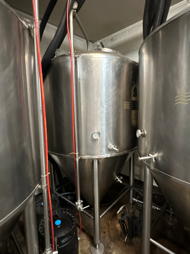 575-GALLON STAINLESS STEEL CONICAL FERMENTER WITH TOP MANWAY, RACKING ARM, SAMPLE VALVE, AND CONE DUMP. UNIT INCLUDES WELDED TRI-CLAMP FITTINGS, PRESSURE GAUGE, AND HEAVY-DUTY FRAME.