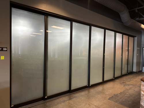 28' X 115" SLIDING GLASS AND METAL PANEL ROOM PARTITION. (8) 42" X 112" PANELS W/ FROSTED TEMPERED GLASS INSERTS.