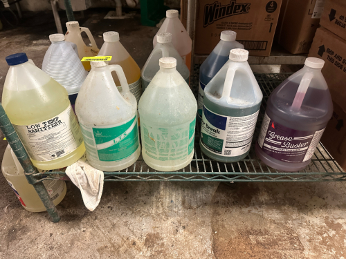 CONTENTS OF BOTTOM SHELF - ASSORTED CLEANING CHEMICALS.