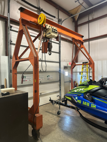 MOBILE STEEL GANTRY CRANE EQUIPPED WITH COFFING 5-TON ELECTRIC CHAIN HOIST AND HEAVY-DUTY STEEL I-BEAM. FEATURES RIGID WELDED FRAME, ROLLING CASTERS FOR SHOP MOBILITY, AND INTEGRATED POWERED HOIST WITH HOOK AND CHAIN AS SHOWN.