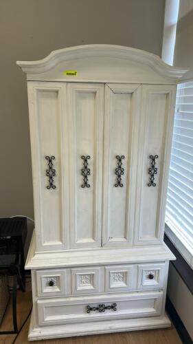 WHITE DISTRESSED ARMOIRE CABINET WITH DOUBLE DOORS AND LOWER DRAWERS. FEATURES CURVED CROWN TOP, FOUR PANEL DOORS WITH DECORATIVE METAL HARDWARE
