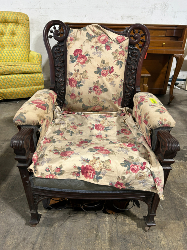 ANTIQUE HIGH BACK ARMCHAIR WITH CARVED WOOD AND WHEELS