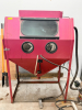 ABRASIVE BLAST CABINET WITH FRONT VIEWING WINDOW AND INTEGRATED GLOVES. INCLUDES FOOT PEDAL CONTROL, INTERNAL GRATE, AND MEDIA HOPPER WITH BOTTOM DRAIN.