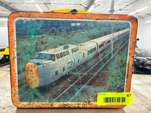 VINTAGE METAL RAILROAD LUNCH PAIL / STORAGE TIN WITH TRAIN GRAPHICS AND CARRY HANDLE. FEATURES CANADIAN NATIONAL (CN) TRAIN IMAGE ON FRONT AND CP RAIL GRAPHICS ON SIDES. INCLUDES YELLOW HANDLE AND METAL LATCH CLOSURE.