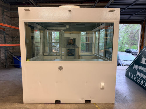 OUTDOOR KIOSK UNIT WITH GLASS SERVICE WINDOWS, INTERIOR CABINETRY, MULTIPLE SINK BASINS, UNDERCOUNTER REFRIGERATION, AND ROOF MOUNTED HVAC UNIT. UNIT FEATURES PAINTED METAL EXTERIOR, ACCESS DOOR, INTERIOR LIGHTING, ELECTRICAL PANEL, AND PLUMBING CONNECTIO