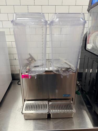 CRATHCO DOUBLE TANK COLD BEVERAGE DISPENSER WITH CLEAR POLYCARBONATE HOPPERS, STAINLESS STEEL BASE, AND DUAL DRIP TRAYS.