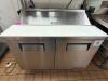 TRUE STAINLESS STEEL SANDWICH PREP TABLE WITH RAISED INGREDIENT RAIL AND DOUBLE DOOR REFRIGERATED BASE. UNIT INCLUDES OVERHEAD SHELF ASSEMBLY AND CUTTING SURFACE WITH LIFT-UP LID. - 2