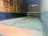 24' DRY VAN TRAILER BODY WITH ROLL-UP REAR DOOR, WOOD INTERIOR WALLS, WOOD FLOORING, AND STEEL FRAME CONSTRUCTION. UNIT SHOWS HEAVY WEAR INCLUDING RUST, CORROSION, SIDE PANEL DAMAGE, AND WEATHERING. REAR LIGHTING PRESENT, SINGLE AXLE CONFIGURATION, AND EX - 7