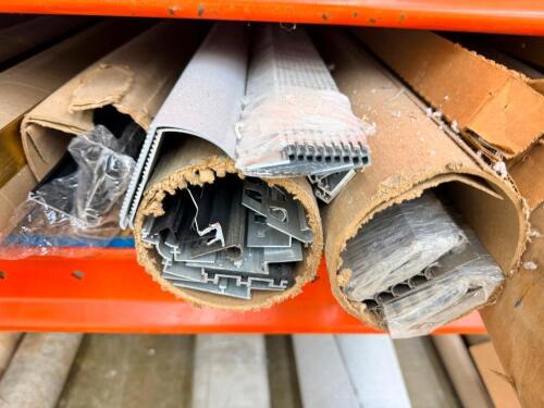 ASSORTMENT OF FLOORING TRANSITION STRIPS AND METAL TRIM PIECES, VARIOUS PROFILES INCLUDING EDGE TRIM AND CHANNELS, MIXED COLORS AND FINISHES, STORED IN CARDBOARD TUBES