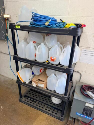 BLACK PLASTIC SHELF W/ CONTENTS - ASSORTED DISTILLED WATER JUGS.