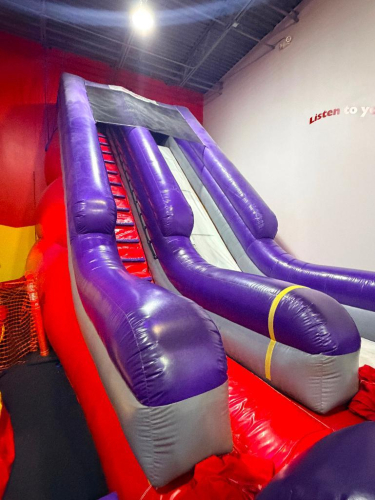 COMMERCIAL-GRADE INFLATABLE DRY SLIDE ATTRACTION, APPROX. 18 FT TALL, FEATURING SINGLE-LANE SLIDE WITH CLIMBING STAIRS, LANDING PAD, AND COMMERCIAL AIR BLOWER.