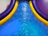 COMMERCIAL INFLATABLE SLIPPERY SLOPE SLIDE WITH PADDED ENTRY, HIGH SIDEWALLS, AND ENCLOSED LANDING AREA. UNIT FEATURES MULTI-COLOR VINYL CONSTRUCTION WITH TOP SAFETY NETTING. - 9