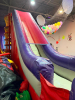 COMMERCIAL INFLATABLE 18 FT SLIDE WITH BLOWER AND ROUND MULTI-LEVEL CLIMBING PLAY STRUCTURE. INCLUDES INFLATABLE SLIDE, BLOWER FAN, METAL FRAME PLAY TOWER, NETTING, AND PADDED SUPPORTS. DISASSEMBLY REQUIRED. - 5