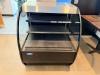 FEDERAL CURVED GLASS REFRIGERATED DISPLAY CASE WITH BLACK FINISH, THREE TIER INTERIOR SHELVING, TEMPERED GLASS SIDES, AND STAINLESS STEEL TOP.