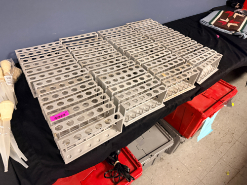 APPROXIMATELY 50 PLASTIC LABORATORY TEST TUBE RACKS. MOLDED CHEMICAL-RESISTANT CONSTRUCTION WITH MULTIPLE TUBE POSITIONS AND LOWER SUPPORT PEGS.