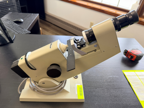 MANUAL LENSOMETER / LENSMETER WITH ADJUSTABLE OPTICAL ALIGNMENT CONTROLS, MEASUREMENT DIALS, AND INTEGRATED EYEPIECE.