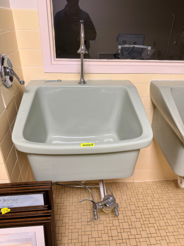 VINTAGE WALL-MOUNT PORCELAIN UTILITY SINK WITH CHROME FIXTURES. PALE GRAY PORCELAIN FINISH WITH EXPOSED PLUMBING AND WALL-MOUNT CONFIGURATION. INCLUDES CHROME FAUCET