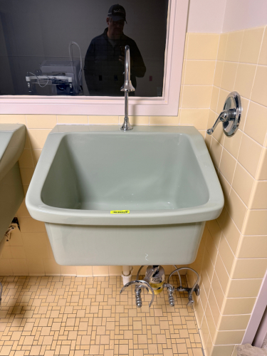 VINTAGE WALL-MOUNT PORCELAIN UTILITY SINK WITH CHROME FIXTURES. PALE GRAY PORCELAIN FINISH WITH EXPOSED PLUMBING AND WALL-MOUNT CONFIGURATION. INCLUDES CHROME FAUCET