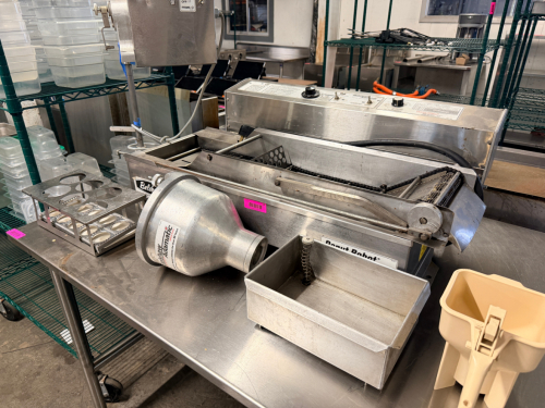 BELSHAW ADAMATIC DONUT ROBOT MARK II AUTOMATIC DONUT FRYER WITH ACCESSORIES. STAINLESS STEEL CONSTRUCTION WITH CONVEYOR FRYING SYSTEM, INCLUDES DEPOSITOR HEAD, HOPPER, PRODUCT TRAY, AND ADDITIONAL ACCESSORY
