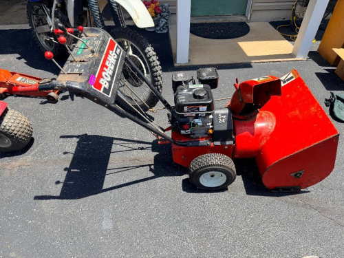 BOLENS FMC TWO-STAGE GAS-POWERED SNOW THROWER WITH 24-INCH CLEARING WIDTH, SELF-PROPELLED DRIVE SYSTEM, AUGER ENGAGEMENT CONTROLS, AND CHUTE DIRECTION ADJUSTMENT. EQUIPPED WITH REPLACEMENT 5 HP GASOLINE ENGINE.