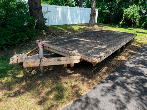 16' WOOD DECK EQUIPMENT TRAILER WITH STEEL FRAME, A-FRAME TONGUE, DROP DECK DESIGN, DUAL AXLE CONFIGURATION, MANUAL JACK, SPARE TIRE MOUNT, AND WOODEN DECKING. TRAILER SHOWS SURFACE RUST, WEATHERING, AND AGE-RELATED WEAR CONSISTENT WITH OUTDOOR STORAGE.