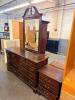 TRADITIONAL BEDROOM FURNITURE SET CONSISTING OF A NINE-DRAWER DRESSER WITH ATTACHED FRAMED MIRROR AND MATCHING THREE-DRAWER NIGHTSTAND.
