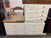 WHITE PAINTED CABINETRY SET CONSISTING OF MULTIPLE BASE CABINET SECTIONS WITH RAISED PANEL FRONTS, BRASS-TONE HARDWARE, AND INTEGRATED STORAGE DRAWERS