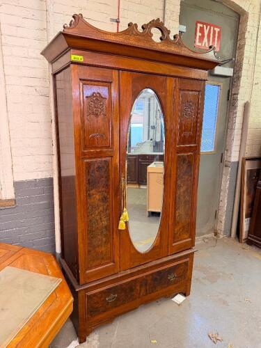 ANTIQUE STYLE ARMOIRE/WARDROBE FEATURING A CARVED CROWN PEDIMENT, CENTRAL OVAL MIRRORED DOOR, DECORATIVE WOOD PANELS, AND A FULL-WIDTH LOWER STORAGE DRAWER. CONSTRUCTED OF WOOD WITH FIGURED VENEER ACCENTS AND TRADITIONAL HARDWARE.
