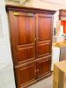 TELEVISION ENTERTAINMENT ARMOIRE WITH RAISED PANEL DOORS AND LOWER STORAGE CABINET IN A CHERRY FINISH. FEATURES FOUR FULL-HEIGHT CABINET DOORS WITH AN INTERIOR TELEVISION COMPARTMENT, ADJUSTABLE SHELVING, AND AN ENCLOSED LOWER STORAGE SECTION