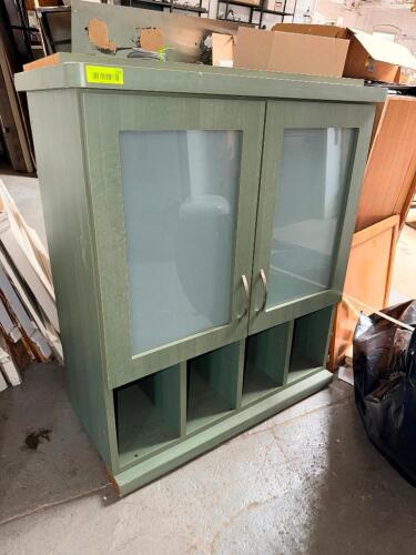 GREEN WOOD STORAGE CABINET WITH FROSTED GLASS DOUBLE DOORS, ADJUSTABLE INTERIOR SHELVES, OPEN CUBBY STORAGE, AND BRUSHED METAL HANDLES.