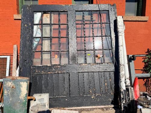 ANTIQUE WOOD INDUSTRIAL STOREFRONT ENTRY WITH DOUBLE DOORS, MULTI-PANE GLAZING, AND TRANSOM. FEATURES HEAVY TIMBER CONSTRUCTION, LARGE LITE DOORS, AND WEATHERED BLACK PAINT