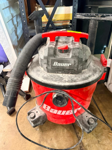 HEAVY-DUTY WET/DRY SHOP VACUUM WITH FLEXIBLE VACUUM HOSE, CARRY HANDLE, FOUR SWIVEL CASTERS, AND ON/OFF POWER SWITCH.