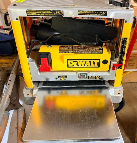 DEWALT 13" THICKNESS PLANER WITH FOLDING INFEED AND OUTFEED TABLES, FOUR-COLUMN DESIGN, CARRY HANDLES, DEPTH ADJUSTMENT CRANK, AND DUST COLLECTION PORT.