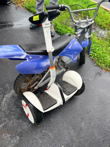SEGWAY SELF-BALANCING PERSONAL TRANSPORTER WITH KNEE CONTROL BAR, DUAL WHEELS, AND RECHARGEABLE BATTERY SYSTEM.