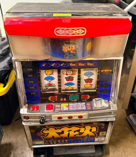 JAPANESE PACHISLOT ARCADE GAMING MACHINE WITH THREE-REEL DISPLAY, DIGITAL READOUT, COIN SLOT, CONTROL BUTTONS, AND DECORATIVE CABINET.