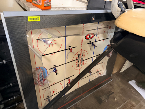 TABLETOP ROD HOCKEY GAME WITH MANUAL PLAYER CONTROL RODS, MOLDED PLAYING SURFACE, AND INTEGRATED GOALS.