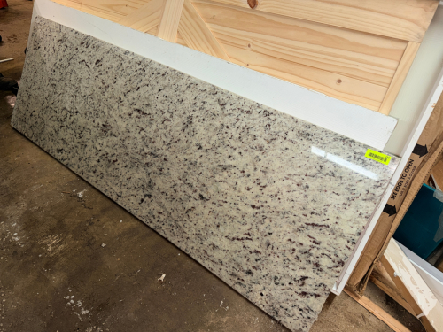 60" X 24" POLISHED NATURAL GRANITE SLAB WITH BEVELED EDGES. LIGHT TAN, CREAM, BLACK, AND BURGUNDY SPECKLED PATTERN.