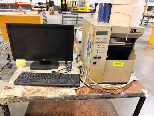 ZEBRA INDUSTRIAL THERMAL LABEL PRINTER WITH HP MONITOR, KEYBOARD, AND ASSORTED LABEL/RIBBON SUPPLIES.