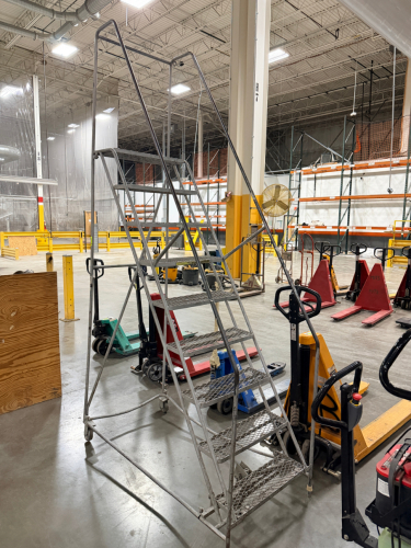ALUMINUM ROLLING SAFETY LADDER WITH LARGE TOP PLATFORM, EXPANDED METAL STEPS, HANDRAILS, AND SWIVEL CASTERS.