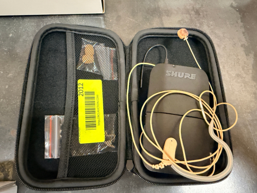 SHURE WIRELESS BODYPACK TRANSMITTER WITH EARSET MICROPHONE, CARRYING CASE, AND ACCESSORIES.