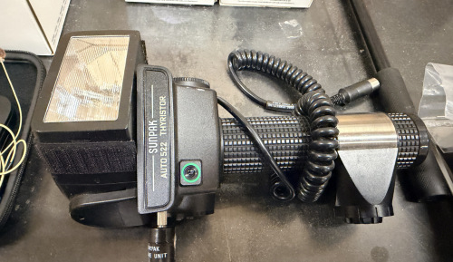 SUNPAK AUTO 522 THYRISTOR HANDLE-MOUNT FLASH WITH COILED SYNC CORD AND BATTERY HANDLE.