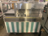 STAINLESS STEEL MOBILE CONCESSION FOOD CART WITH ENCLOSED STORAGE, OVERHEAD DISPLAY FRAME, SERVING SHELF, THREE PAN WELLS, DOUBLE BASIN HAND SINK, LOCKING CASH DRAWER, AND ROLLING CASTERS. UNIT FEATURES A STAINLESS STEEL CONSTRUCTION WITH VINYL SKIRTING - 6
