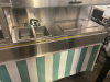 STAINLESS STEEL MOBILE CONCESSION FOOD CART WITH ENCLOSED STORAGE, OVERHEAD DISPLAY FRAME, SERVING SHELF, THREE PAN WELLS, DOUBLE BASIN HAND SINK, LOCKING CASH DRAWER, AND ROLLING CASTERS. UNIT FEATURES A STAINLESS STEEL CONSTRUCTION WITH VINYL SKIRTING - 7