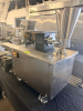 STAINLESS STEEL ELECTRIC AUTOMATIC DUMPLING / RAVIOLI FORMING MACHINE WITH STUFFING HOPPER, DOUGH HOPPER, FORMING ROLLER ASSEMBLY, CONVEYOR DISCHARGE, AND LOCKING SWIVEL CASTERS. UNIT FEATURES ADJUSTABLE STUFFING VOLUME CONTROL.