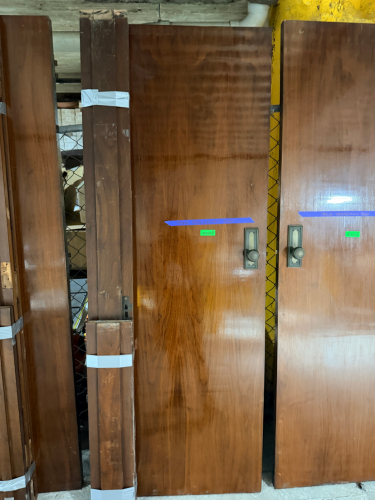 VINTAGE SOLID WOOD DOOR WITH DARK BROWN FINISH, CONTRASTING DECORATIVE INLAY, MATCHING WOOD TRIM COMPONENTS, AND PERIOD-STYLE METAL HARDWARE. DOOR FEATURES A RECTANGULAR RECESSED DECORATIVE BORDER, ROUND METAL KNOB, RECTANGULAR BACKPLATE, KEYHOLE, AND MOR