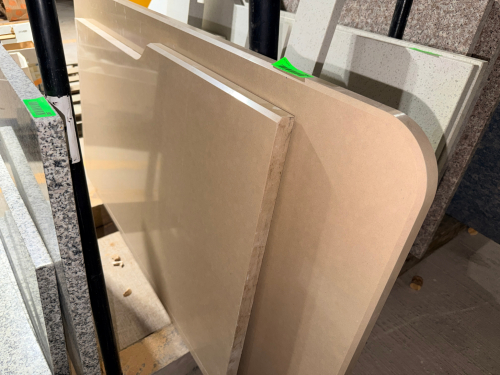 (2) BEIGE ENGINEERED STONE / QUARTZ COUNTERTOP SLABS WITH FINE SPECKLED PATTERN AND POLISHED FINISH. INCLUDES ONE RECTANGULAR PIECE AND ONE LARGER SHAPED PIECE WITH ROUNDED END AND FINISHED EDGES.