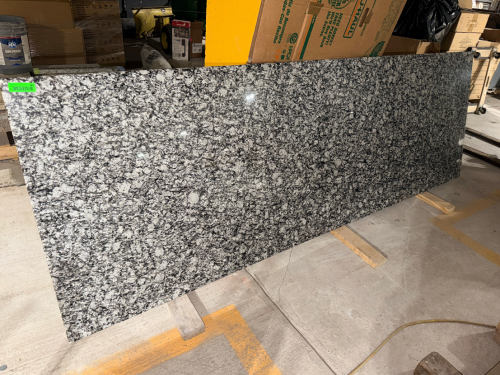 BLACK, WHITE, AND GRAY NATURAL GRANITE COUNTERTOP SLAB WITH POLISHED FACE AND FINISHED EDGES. HIGH-CONTRAST STONE PATTERN WITH LARGE WHITE MINERAL FORMATIONS AND BLACK / DARK GRAY VEINING.