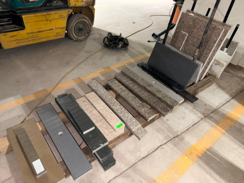 ASSORTED NATURAL STONE AND ENGINEERED STONE COUNTERTOP / VANITY COMPONENTS INCLUDING GRANITE, QUARTZ, AND SOLID-SURFACE SECTIONS IN MULTIPLE COLORS AND PATTERNS. LOT INCLUDES RECTANGULAR TOPS, BACKSPLASH / EDGE STRIPS, NARROW FABRICATED SECTIONS, AND PIEC